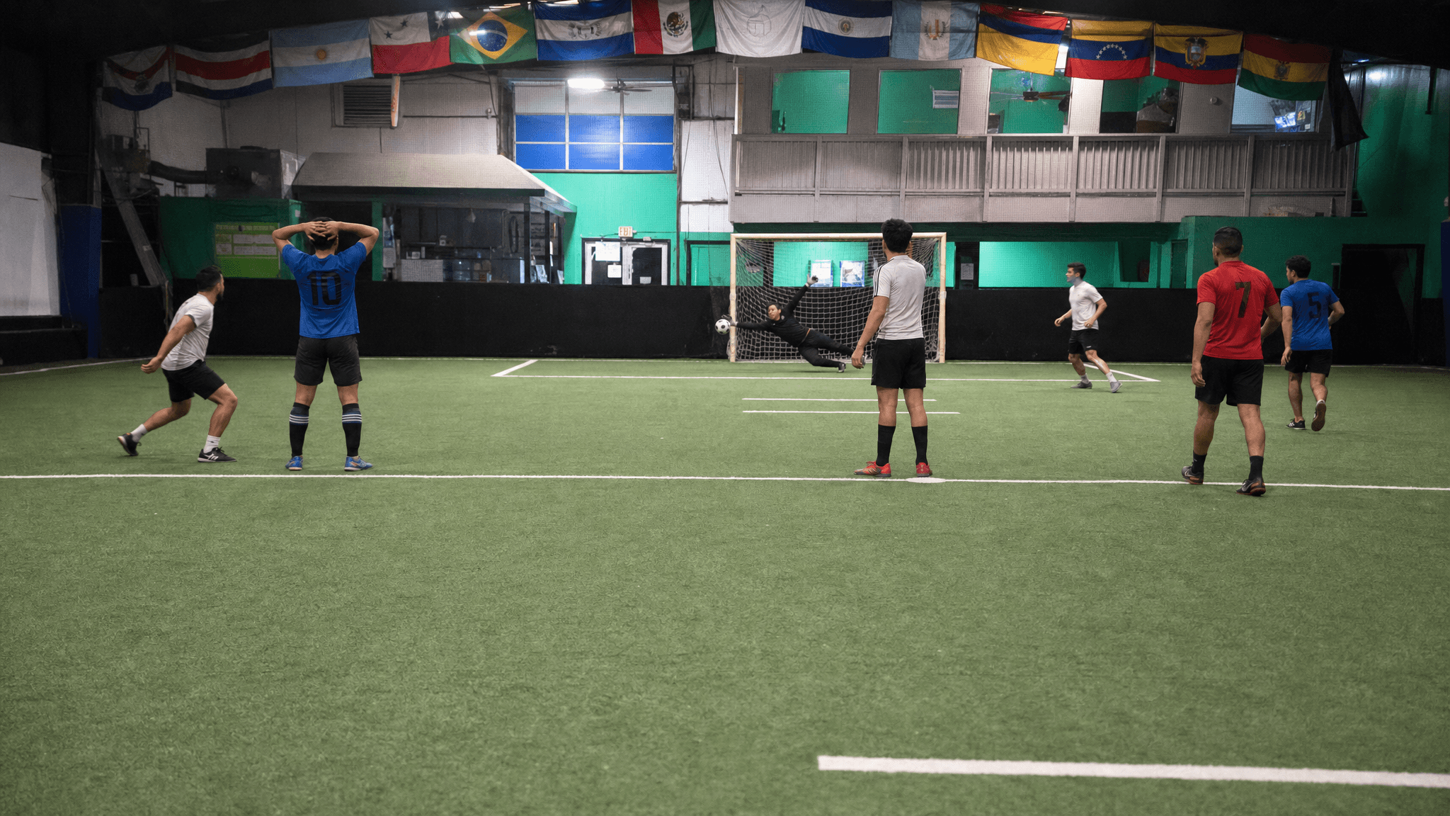 UPlay Indoor Soccer pitch — a full-sided game in progress under the flags