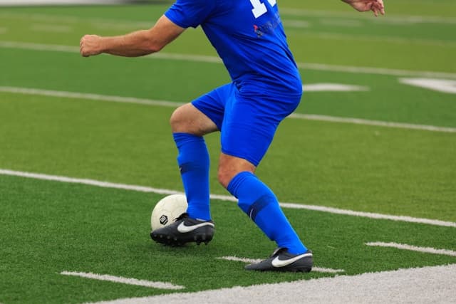 Player in blue dribbling on turf